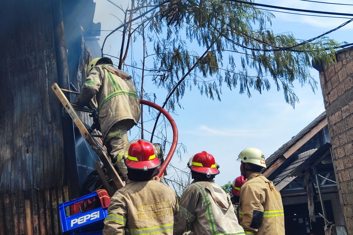 Personil Damkar Kota Depok bahu-membahu padamkan api yang lahap gudang rongsok di belakang Margocity Depok, Selasa (5/12/2023).