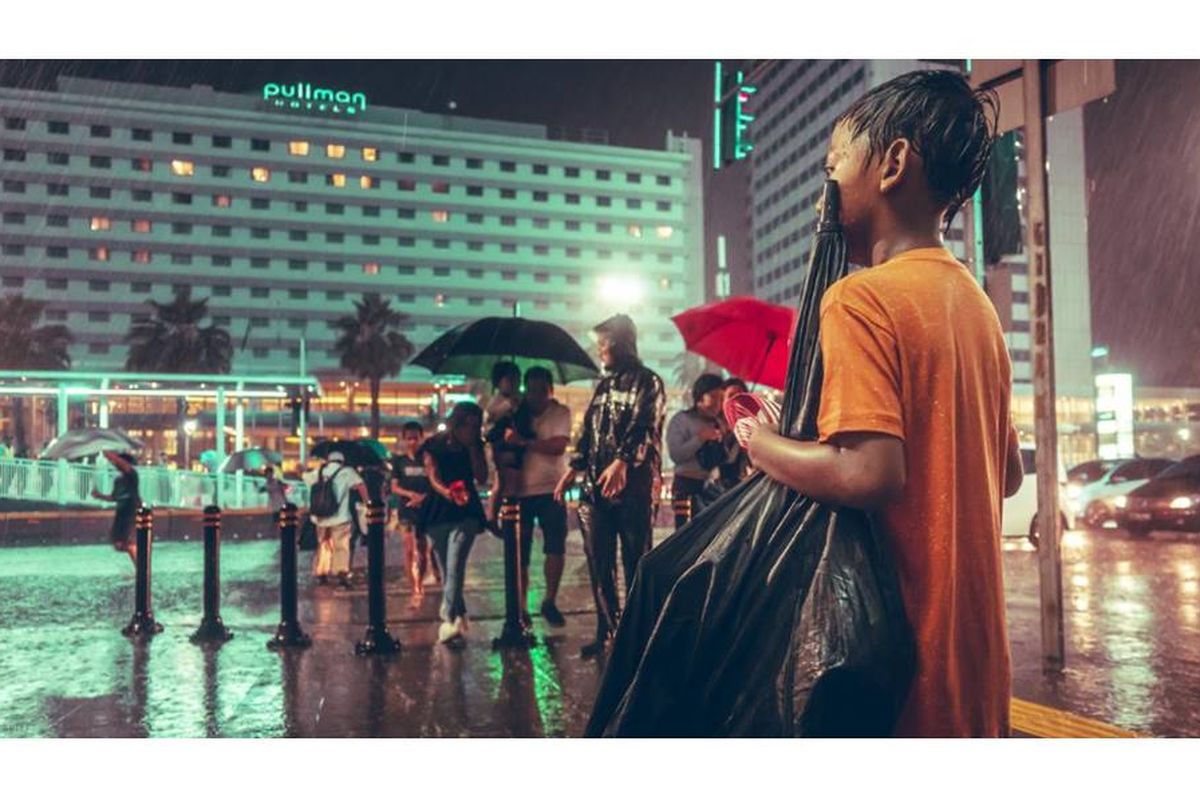 Foto seorang anak yang tengah mencari uang dengan menjadi ojek payung di Jakarta