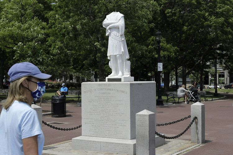 Seorang pengguna jalan melintasi patung Christopher Columbus yang dipenggal di Boston, Amerika Serikat (AS), Rabu (10/6/2020). Patung itu dipenggal di tengah demo George Floyd yang menyerukan penghapusan simbol perbudakan dan penjajahan.