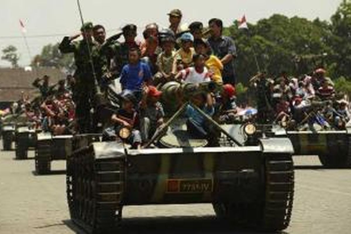 Warga mengikuti defile pasukan dengan menaiki tank saat peringatan HUT ke-67 Tentara Nasional Indonesia di lapangan Jenderal Soedirman, Ambarawa, Kabupaten Semarang, Jawa Tengah, Jumat (5/10/2012).  