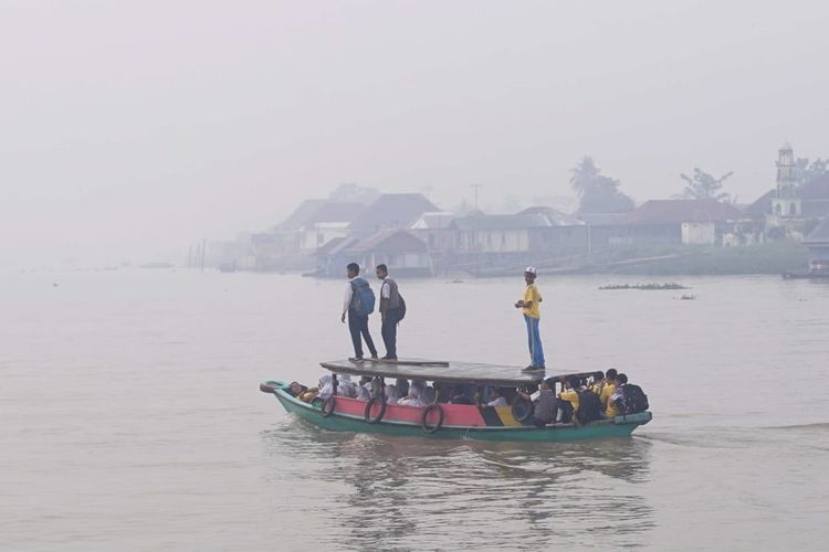 Para pelajar SMP menyebrangi sungai Musi untuk menuju ke sekolah. Kondisi kabut asap yang kian pekat itu, menyebabkan jarak pandang di sungai menjadi terganggu, Selasa (17/9/2019).