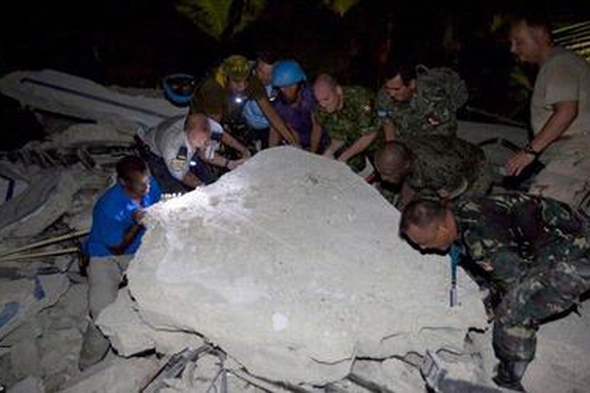 Beberapa petugas dari regu penyelamat berupaya menyelamatkan mereka yang terbenam di bawah reruntuhan bangunan PBB di Port-au-Prince, Haiti 