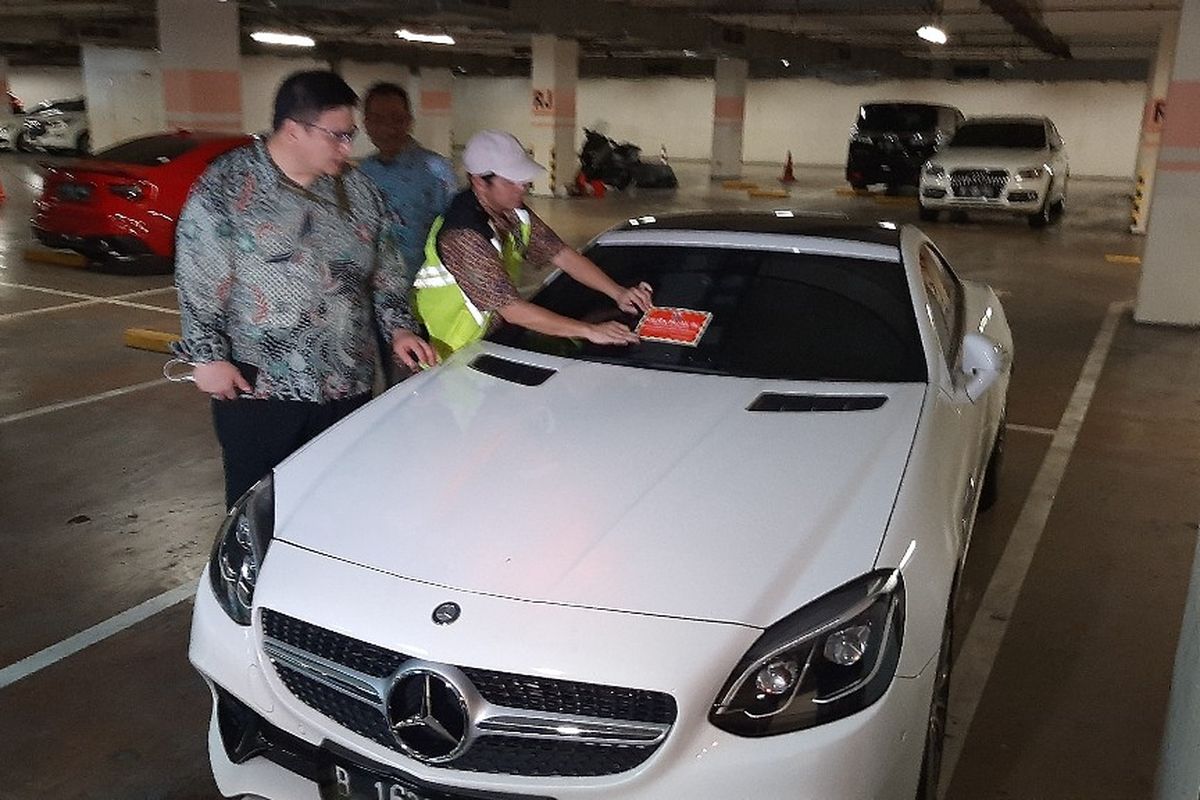 Petugas menempelkan stiker ke mobil mewah bermerek Mercedes yang pajaknya belum dibayar di Apartemen Regatta, Jakarra Utara, Kamis (5/12/2019).