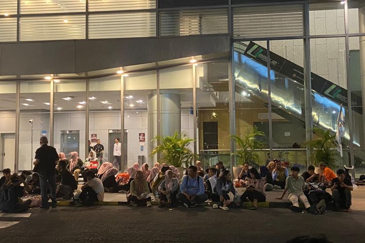 Pendukung Khofifah-Emil yang bersantai di luar gedung tanpa menonton live streaming debat ketiga Pilgub Jatim 2024, Senin malam (18/11/2024).