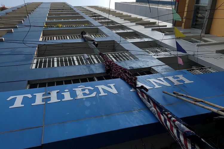 Untaian kain yang disambung digunakan penghuni apartemen untuk menyelamatkan diri dari gedung yang terbakar di Ho Chi Minh, Vietnam, Jumat (23/3/2018).
