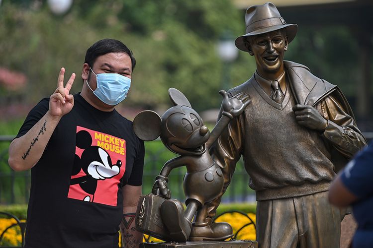 Pengunjung mengenakan masker saat mendatangi taman hiburan Disneyland, Shanghai, China, yang baru dibuka kembali, Senin (11/5/2020). Shanghai Disneyland resmi kembali dibuka setelah ditutup selama 4 bulan akibat pandemi virus corona.