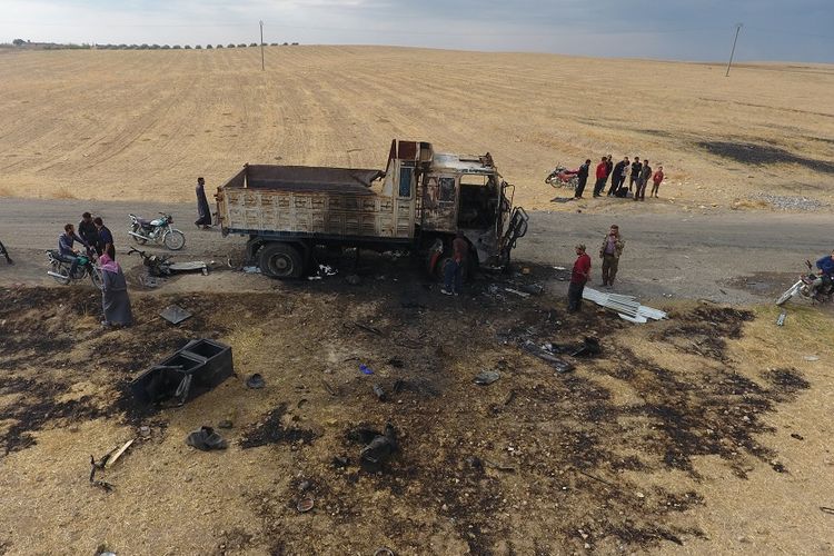 Warga Suriah melihat sebuah truk yang hancur di desa Ayn al-Bayda, Suriah utara, di mana juru bicara ISIS, Abu Hassan al-Muhajir, dilaporkan tewas dalam sebuah serangan.