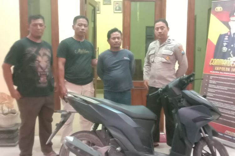 Pelaku (tengah) berikut barang bukti sepeda motor hasil curian diamankan di kantor Polsek Karanggeneng, Lamongan, Jawa Timur, usai kepergok coba menawarkan sepeda motor tersebut melalui media sosial (medsos), Minggu (15/9/2024).