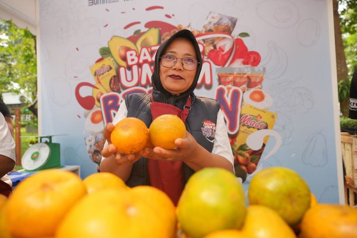 Ketua Klaster Jeruk Sungai Penuh Wartini sedang memegang dua buah jeruk hasil panen dari Klaster Jeruk Sungai Penuh di Jambi. 