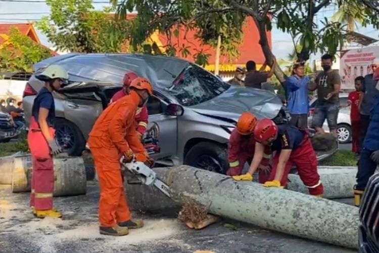 Petugas mengevakuasi mobil yang menabrak pohon palem hingga tumbang di Jalan Diponegoro, Kota Pekanbaru, Riau, Rabu (5/1/2021).