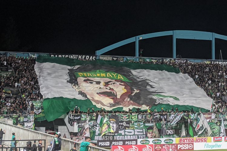 Suporter fanatik Persebaya Surabaya atau Bonek mengibarkan bendera raksasa. Laga PSS Sleman vs Persebaya pada lanjutan pekan tujuh Liga 1 2022-2023 digelar di Stadion Maguwoharjo, Sleman, pada Sabtu (27/8/2022) malam WIB.