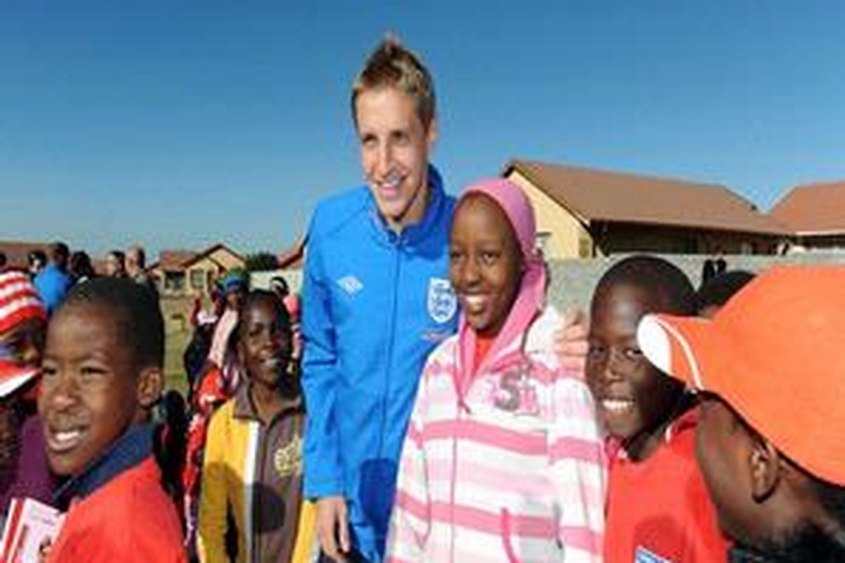 Pemain Inggris, Michael Dawson, berpose dengan anak-anak di Rustenburg, Afrika Selatan.