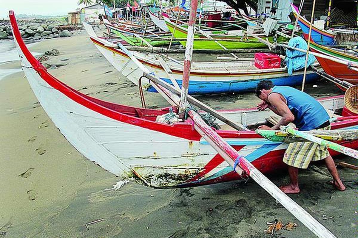 Seorang nelayan di kawasan Pantai Purus, Kota Padang, Sumatera Barat, Minggu (11/3), membersihkan kapal yang biasa digunakan untuk mencari ikan. Cuaca buruk membuat nelayan tidak bisa melaut dan terpaksa berdiam di pinggir pantai, menanti cuaca membaik.