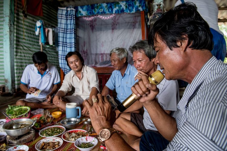 Foto tertanggal 13 Juli 2017, memperlihatkan Tang Van Cuol (kanan) di Mekong Delta, Vietnam, bernyanyi dengan mic untuk karaoke memakai ponselnya, saat menikmati hidangan spesial bersama para petambak udang lainnya, dalam menyambut seorang teman yang baru pulang dari China.