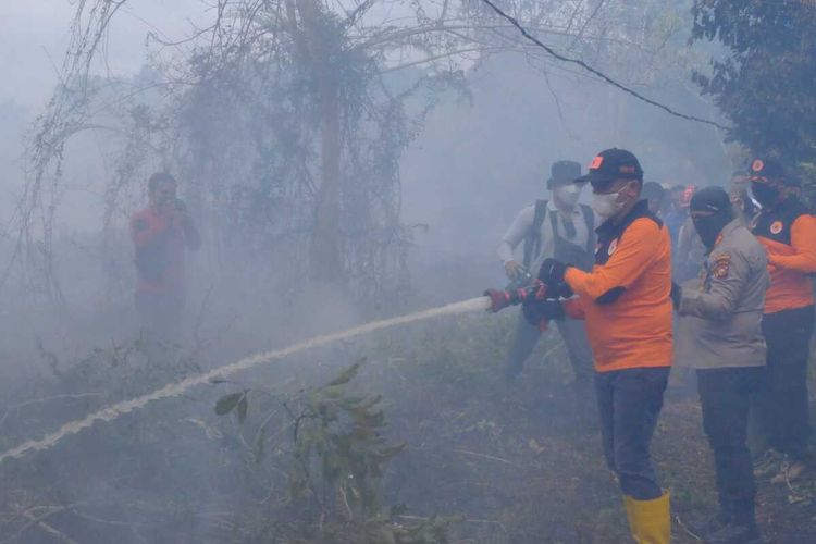 Bupati Kepulauan Meranti, Muhammad Adil bersama Kapolres Kepulauan Meranti AKBP Andi Yul LTG ikut berjibaku memadamkan api karhutla di Desa Bokor, Kecamatan Rangsang Barat, Kabupaten Kepulauan Meranti, Riau, Senin (17/1/2022).