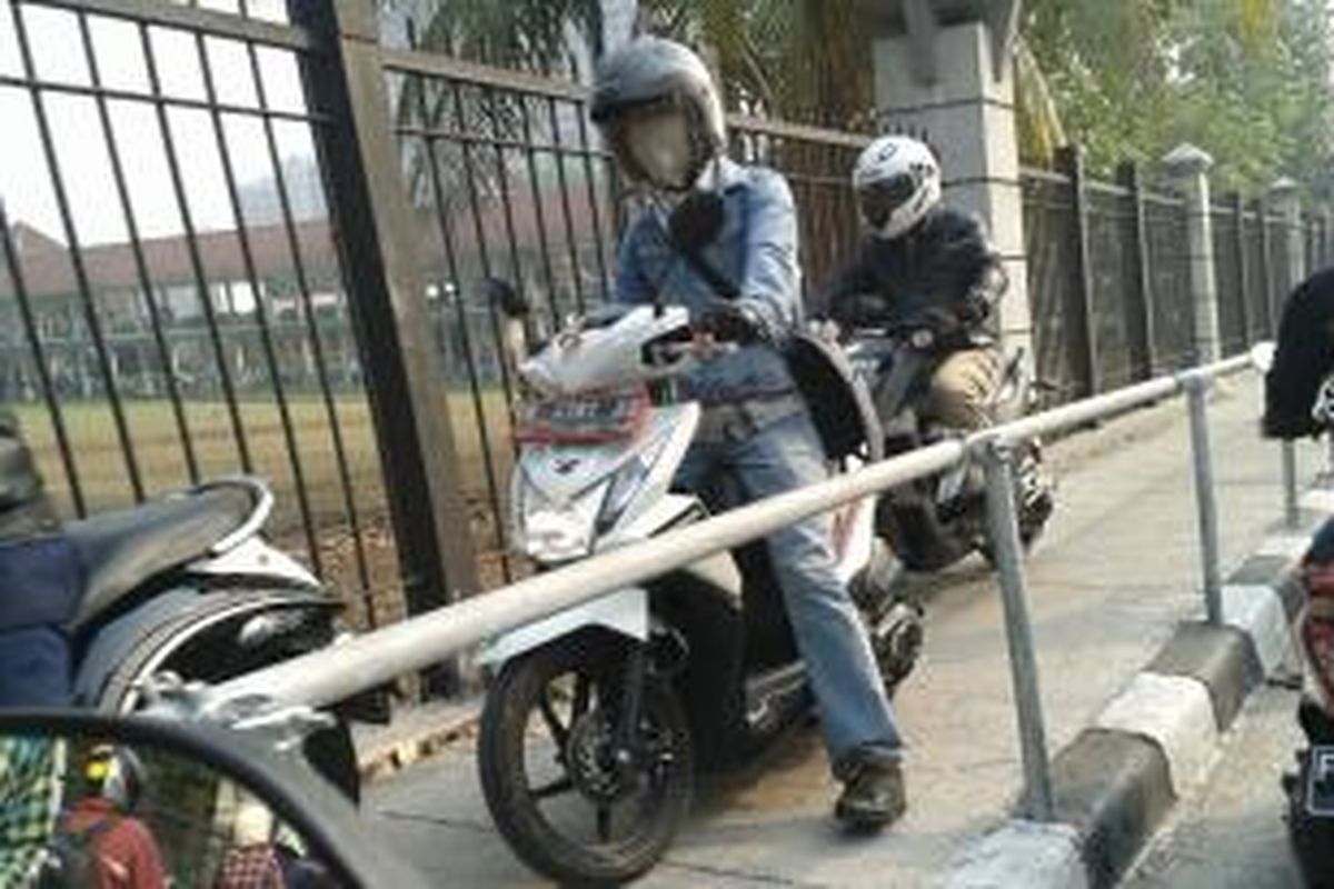 Pengendara sepeda motor menggunakan trotoar untuk menghindari kemacetan.