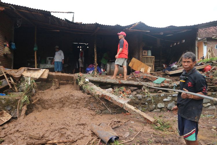 Warga Desa Banjaragung, Kecamatan Bareng, Kabupaten Jombang, Jawa Timur, membersihkan sampah sisa banjir serta memperbaiki rumahnya yang rusak akibat bandang, Selasa (2/2/2021).