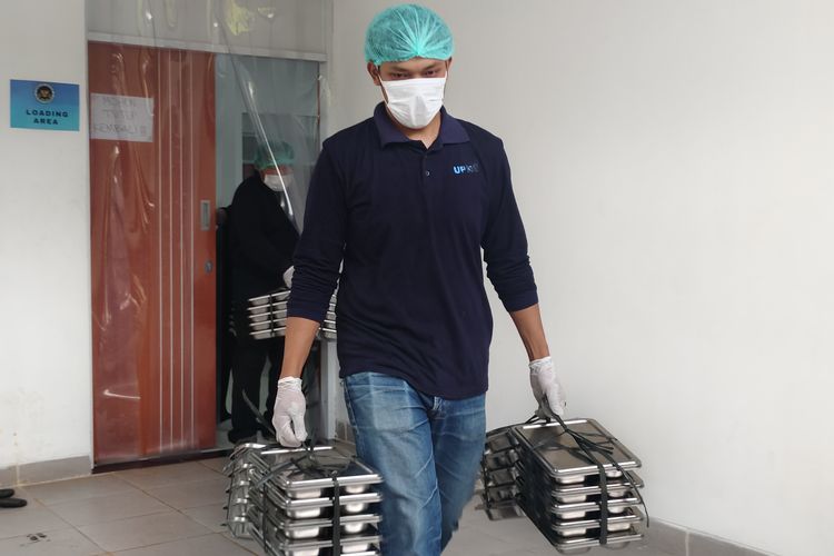 Portrait of an officer lifting a Free Meal Program (PMG) ovreng to be transferred to a container, at the Palmerah Nutrition Services Fulfillment Unit (SPPG), West Jakarta this morning, Monday (6/1/2025). 