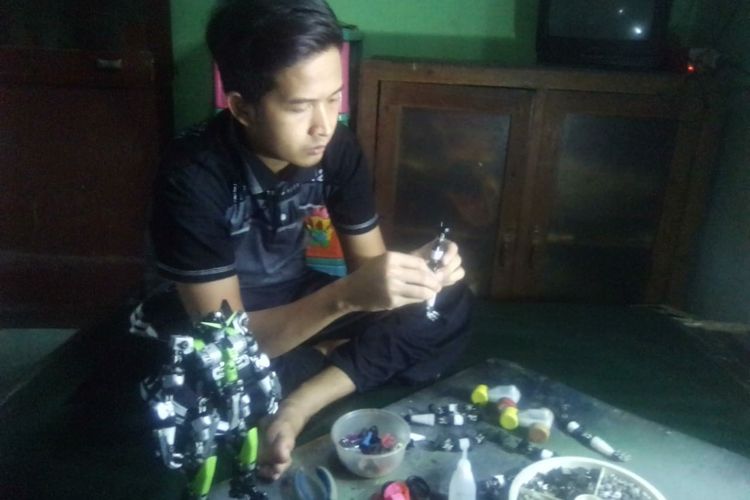 Edi Santoso saat merakit robot mainan dari korek bekas.