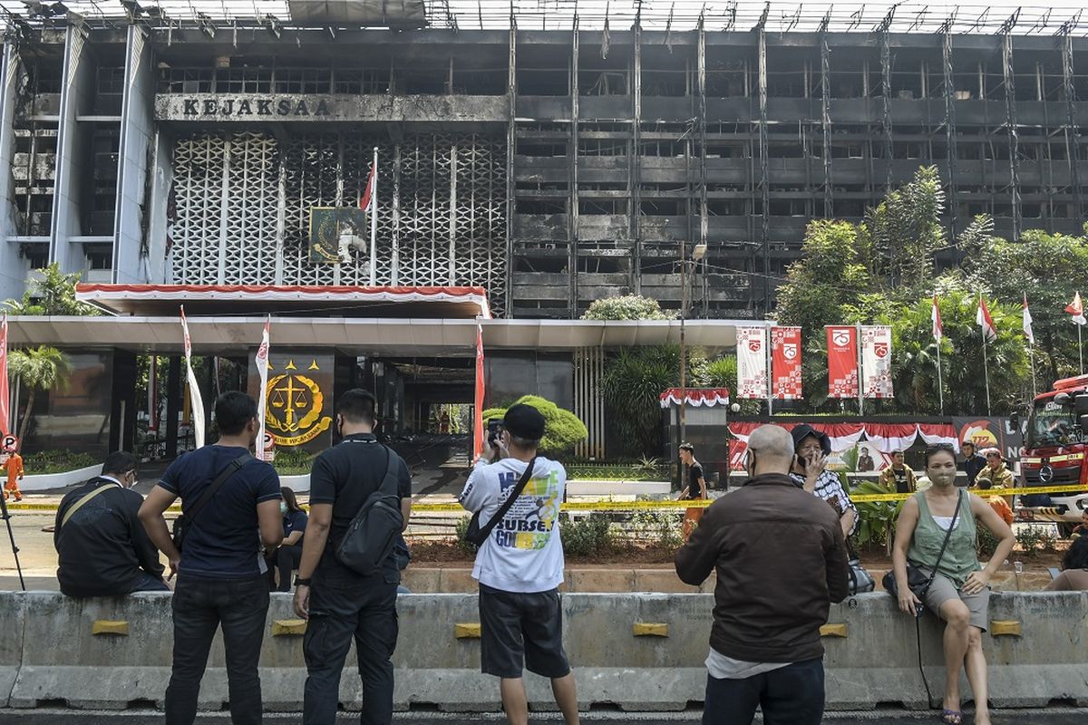 Warga menyaksikan petugas pemadam kebakaran melakukan proses pendinginan di gedung utama Kejaksaan Agung yang terbakar di Jakarta, Minggu (23/8/2020). Direktur Reserse Kriminal Umum Polda Metro Jaya Kombes Pol Tubagus Ade Hidayat mengatakan petugas dari tim laboratorium forensik (Labfor) dan Inafis menunda olah tempat kejadian (TKP) kebakaran gedung Kejaksaan Agung karena terkendala asap sehingga belum dapat menjangkau secara keseluruhan lokasi kebakaran dan rencananya olah TKP akan dilakukan pada Senin (24/8/2020). ANTARA FOTO/Galih Pradipta/aww.