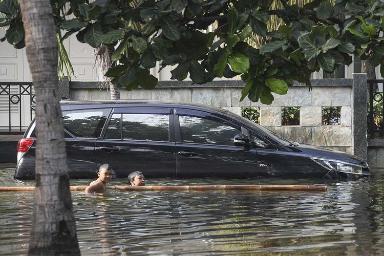 Dua anak bermain air saat banjir rob menggengangi Kompleks Pantai Mutiara, Penjaringan, Jakarta, Minggu (7/6/2020). Banjir di kawasan tersebut diduga akibat adanya tanggul yang jebol saat naiknya permukaan air laut di pesisir utara Jakarta.