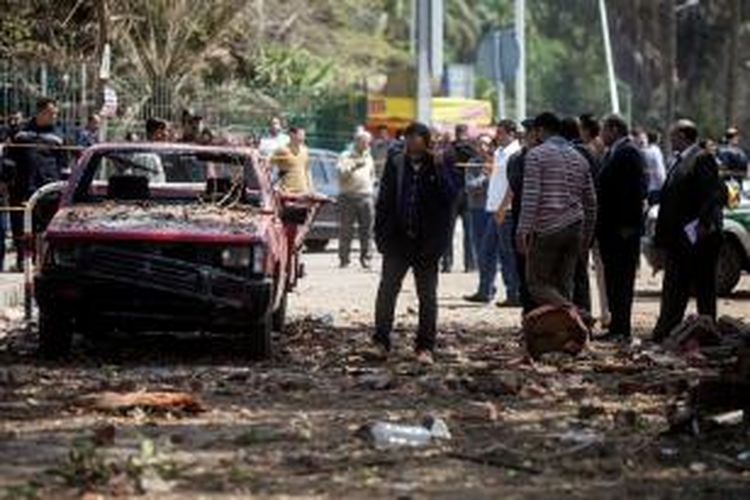 Aparat keamanan Mesir memeriksa sebuah mobil yang hancur akibat serangan dua bom bunuh diri di dekat Universitas Kairo, Rabu (2/4/2014). Insiden itu menewaskan dua orang, salah satunya adalah seorang jenderal kepolisian Mesir.