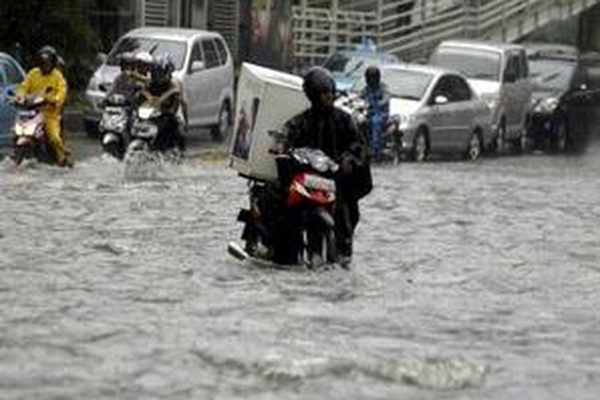 Pengendara motor terpaksa menuntun kendaraannya yang magok akibat hujan deras di Jalan MH Thamrin, Jakarta Pusat, Senin (8/6).