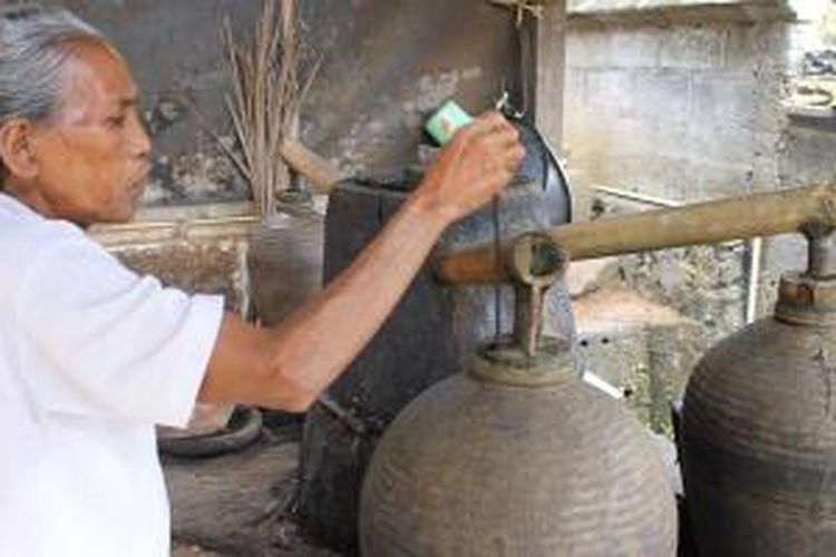 Ni Ketut Murti sedang melihat volume arak yang sudah tersimpan dengan batang kayu sebagai alat ukur. Pembuatan arak secara tradisional ini masih bisa dijumpai di Desa Tri Eka Bhuana, Kecamatan Sidemen, Kabupaten Karangasem, Bali.