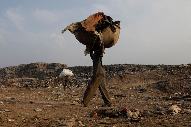 Mansoor Khan, 44, seorang pemungut sampah, berjalan ketika ia membawa sekarung bahan yang dapat didaur ulang setelah menyelesaikan pekerjaan untuk hari itu di tempat pembuangan sampah, selama pandemi penyakit virus corona (COVID-19), di New Delhi, India, 9 Juli 2020 .