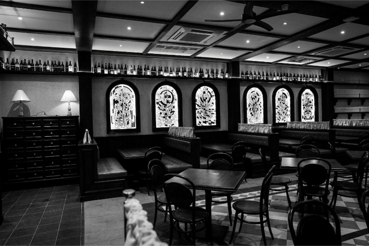 Interior Rosa Osteria menampilkan desain bergaya rustic-modern dengan jendela kaca patri dan tata pencahayaan hangat, menciptakan suasana homey yang nyaman bagi para pengunjung