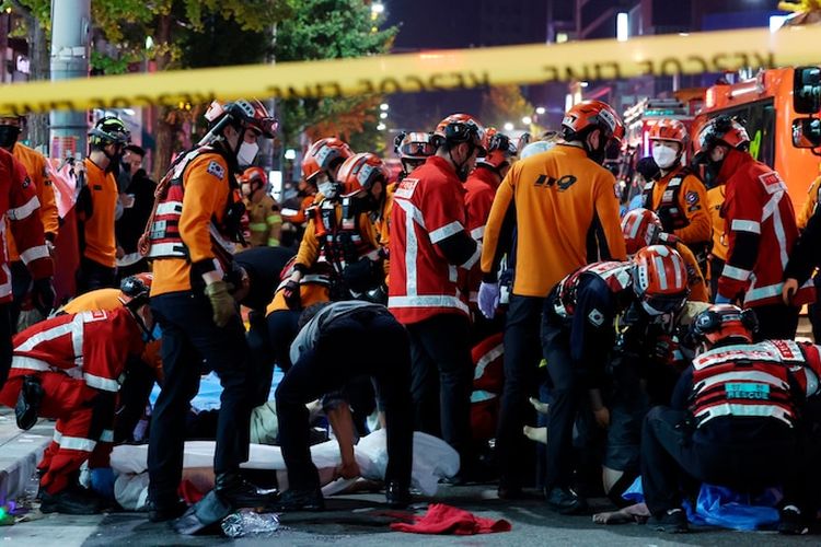 Petugas penyelamat dan pemadam kebakaran bekerja di lokasi tragedi Halloween Itaewon. Seoul, Korea Selatan, Sabtu (29/10/2022). Sedikitnya 149 orang tewas setelah mengalami serangan jantung, sesak napas akibat berhimpitan di gang sempit dan jalan berliku bersama ribuan orang.
