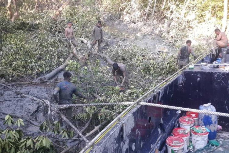 Polisi bergelimang lumpur saat proses evakuasi kapal hantu di hutan bakau Padang Jati OKI, Sumsel, Jumat (11/6/2021).