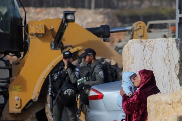 Seorang wanita memeluk seorang bayi ketika ekskavator tentara Israel menghancurkan dua rumah Palestina di daerah Jabal Johar kota Hebron, dekat pemukiman Israel Kiryat Arba, di Tepi Barat yang diduduki, pada 28 November 2022. Dewan Keamanan PBB dengan suara bulat pada Senin (20/2) menyetujui pernyataan yang sangat menentang pembangunan berkelanjutan dan perluasan permukiman Israel.