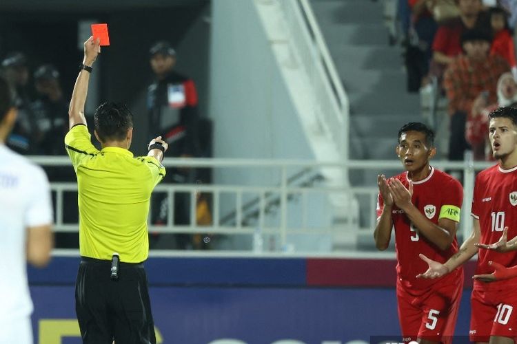 Wasit asal China Shen Yinhao memberikan kartu merah kepada bek Indonesia Rizky Ridho (#5) pada pertandingan semifinal Piala Asia U23 2024 antara Indonesia vs Uzbekistan di Stadion Abdullah Bin Khalifa di Doha pada 29 April 2024. (Foto oleh KARIM JAAFAR / AFP)