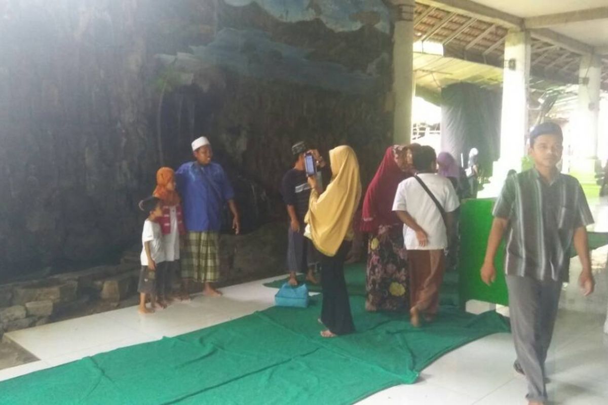 Peziarah foto-foto depan air barokah di dekat makam.