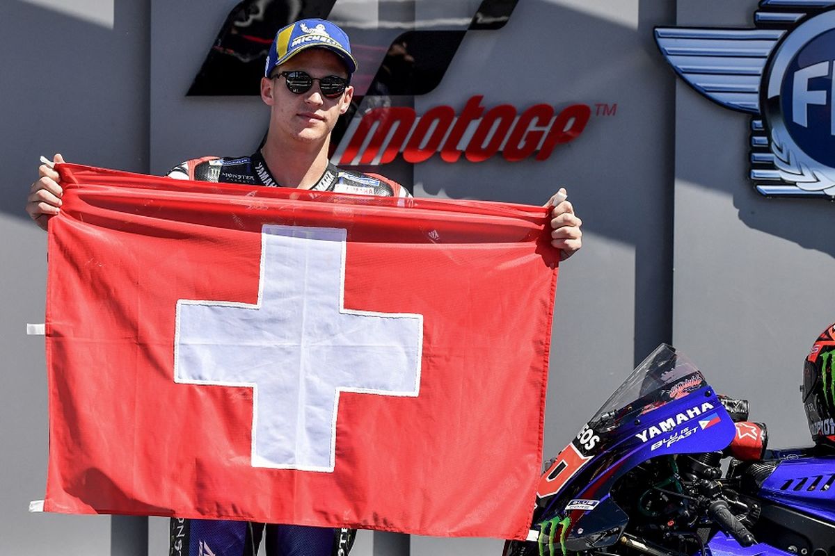 Pebalap Yamaha Fabio Quartararo berpose dengan bendera Swiss sebagai penghormatan untuk pebalap Moto3 Jason Dupasquier, yang meninggal pada usia 19 tahun, karena kecelakaan di kualifikasi Moto3 pada balapan Grand Prix Italia di Mugello pada 30 Mei 2021.