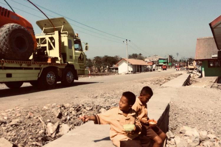 Dua Orang Siswa SD Gading Asri, Gading, Playen, Gunungkidul, tengah Beristirahat dibelakangnya Alat Berat melintas Junat (5/10/2018)