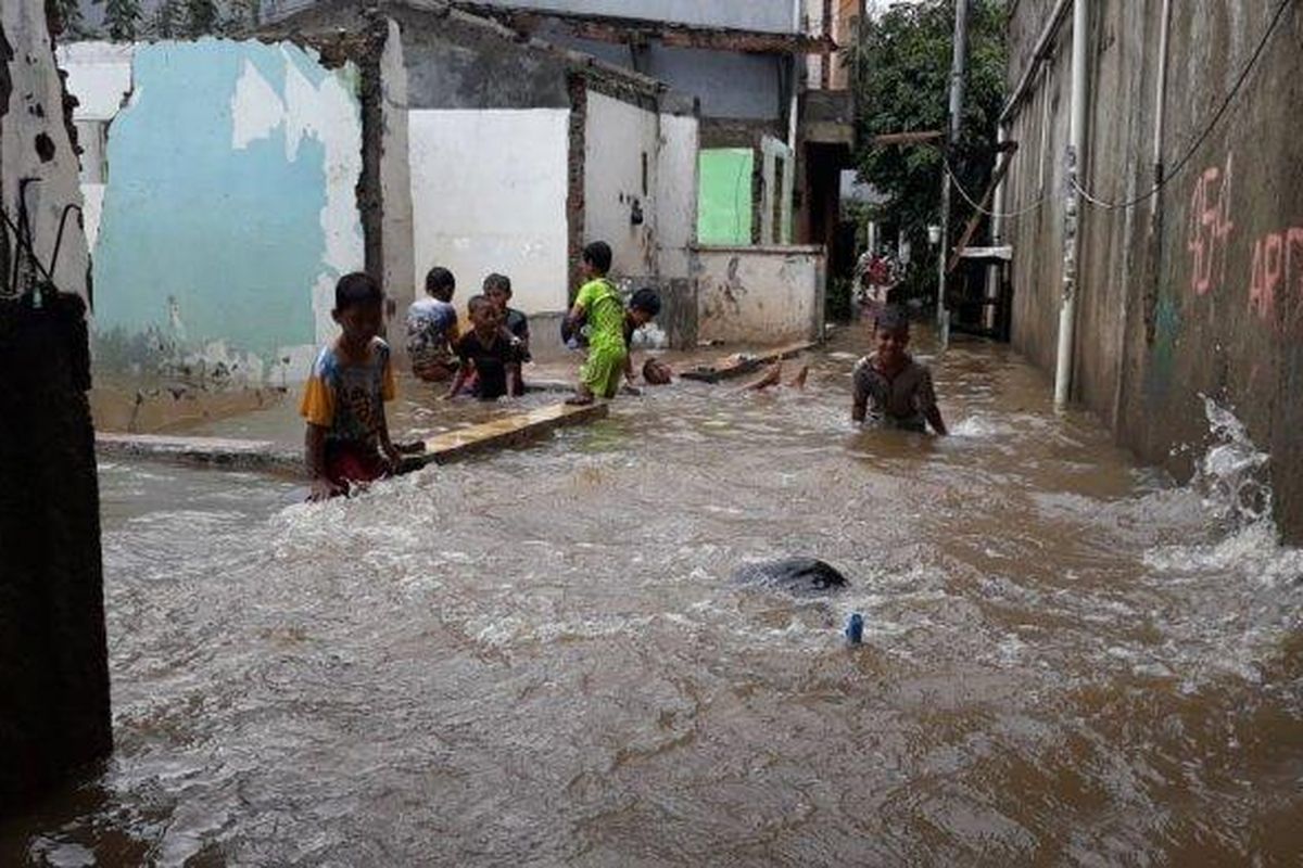 Sejumlah anak-anak tengah bermain di tengah banjir yang melanda Pemukiman di RT 001/03 Cipinang Melayu, Makasar, Jakarta Timur pada Selasa (16/2/2021). 