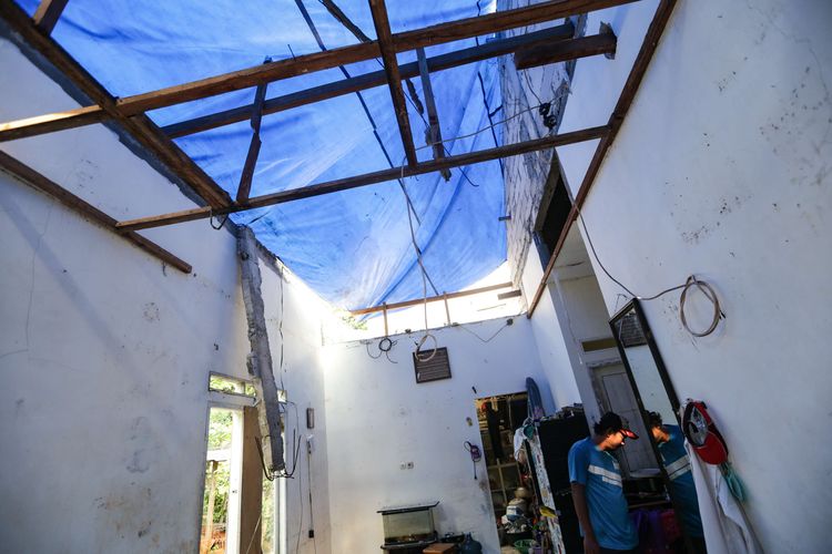 Warga memasang tenda untuk menutup atap rumah warga di Jalan Kebon Kopi RT 001 RW 007, Pengasinan, Sawangan, Depok, rusak akibat diterpa angin puting beliung pada Senin (10/10/2022). Kerusakan akibat puting beliung Minggu (9/10/2022) didominasi di bagian atap.