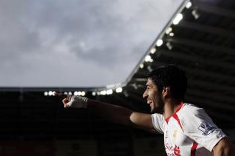 Penyerang Liverpool Luis Suarez merayakan salah satu dari dua golnya ke gawang Cardiff City, pada pertandingan Premier League, di Cardiff City Stadium, Sabtu (23/3/2014).