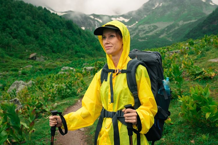 Ilustrasi memakai jas hujan saat trekking.