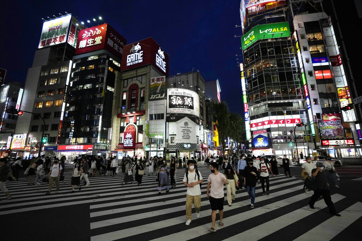 Orang-orang berjalan di sepanjang penyeberangan pejalan kaki Jumat, 30 Juli 2021, di Tokyo, ketika Perdana Menteri Jepang Yoshihide Suga memperluas keadaan darurat virus corona ke empat wilayah lagi selain Tokyo menyusul rekor lonjakan infeksi saat ibu kota menjadi tuan rumah Olimpiade.