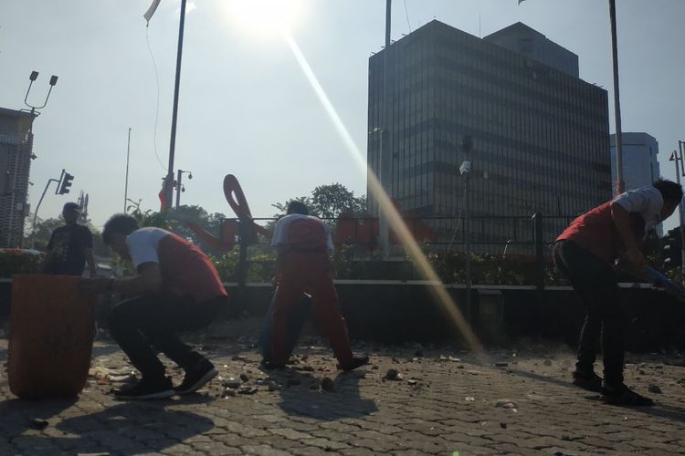 Petugas kebersihan di sekitar kawasan Sarinah membersihkan sampah batu yang digunakan para perusuh  di depan Bawaslu, Jakarta Pusat, Rabu (22/5/2019) malam.