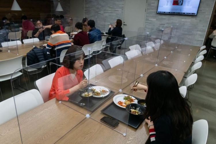 Karyawan di Seoul makan siang di kantin yang diberi pembatas. 