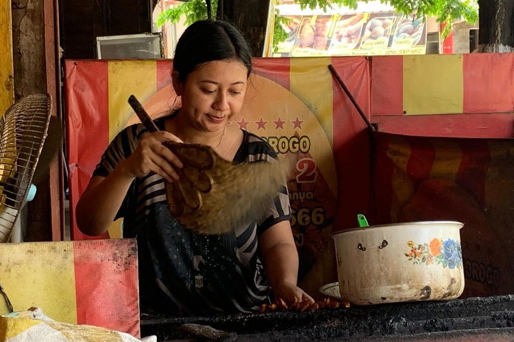 BAKAR SATE--Pemilik Sate Ayam Ngepos Pak Sipbun 2, Sari sementara membakar daging sate ayam sebelum disajikan ke konsumennya. 