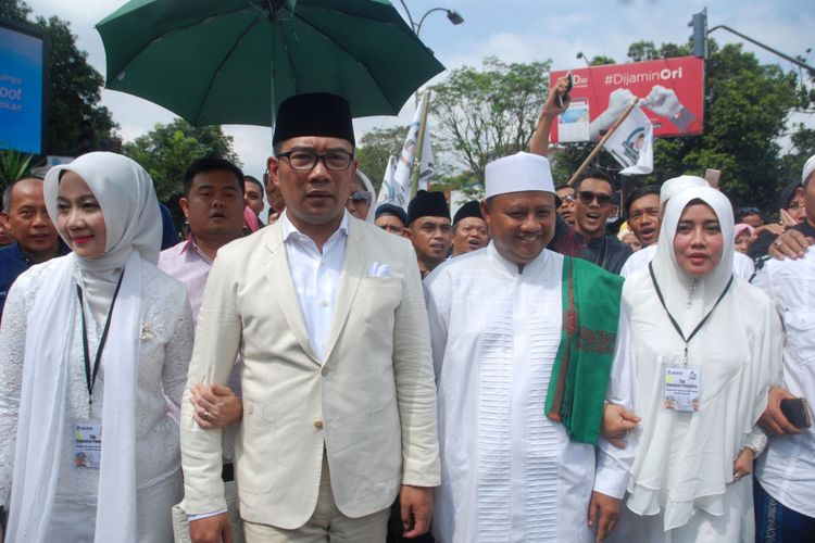 Bakal calon gubernur dan wakil gubernur Jawa Barat 2018 Ridwan Kamil (kedua kiri) dan Uu Ruzhanul Ulum (kedua kanan) atau disebut pasangan RK-Uu (Rindu) melakukan konvoi dengan berjalan kaki usai melaksanakan salat hajat menuju kantor KPUD Jabar, di Bandung, Jawa Barat, Selasa (9/1/2018). Pasangan RK-Uu bersama empat partai politik koalisi Nasdem, PPP, PKB, Hanura beserta simpatisan mendatangi KPUD Jabar guna melakukan pendaftaran untuk maju dalam Pilgub Jabar 2018.