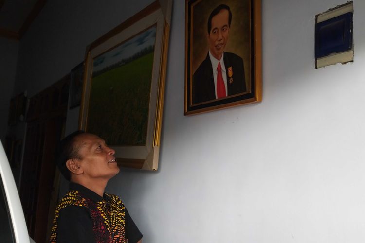 Agus Yusuf, pelukis difabel asal Desa Sidomulyo, Kecamatan Sawahan, Kabupaten Madiun yang melukis menggunakan mulut dan kakinya menunjukan karyanya lukisanya berupa foto presiden ketujuh RI, Joko Widodo.