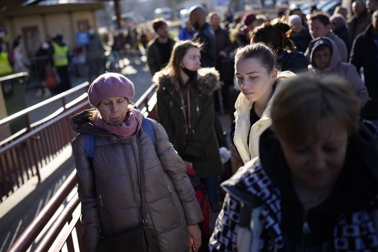 Orang-orang menunggu dalam antrean untuk naik kereta yang berangkat ke Lviv di Ukraina di stasiun kereta api di Przemysl, Polandia, Senin (14/3/2022). Sementara puluhan ribu orang telah meninggalkan Ukraina setiap hari sejak invasi Rusia, sejumlah kecil tetapi terus bertambah sedang menuju ke arah lain. Awalnya mereka adalah sukarelawan asing, pria ekspatriat Ukraina yang akan berperang, dan orang-orang yang mengirimkan bantuan. Tapi semakin ke sini, perempuan juga menuju kembali. 