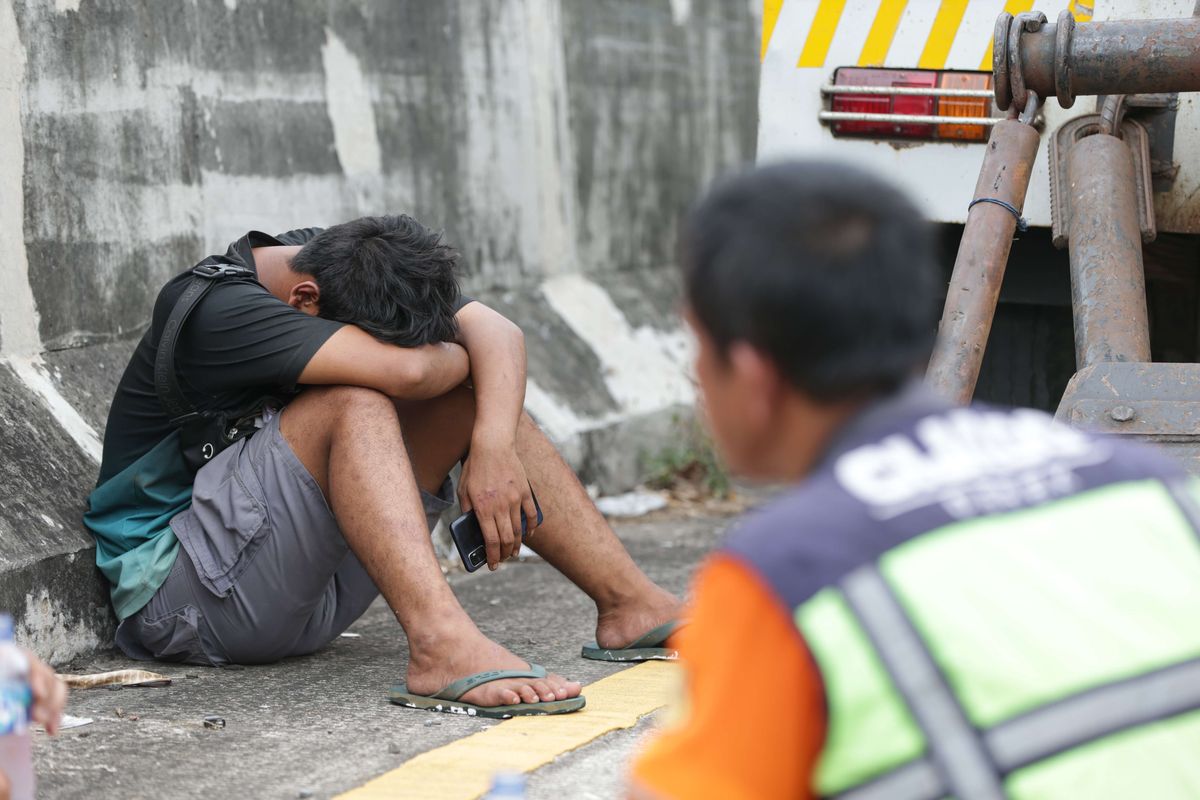 Sopir truk kontainer bermuatan cat yang terguling di pintu keluar tol Cijago di Jalan Juanda, Depok, tertunduk lesu usai kecelakaan, Kamis (10/11/2022). Kecelakaan tunggal itu dipastikan tak ada korban jiwa maupun luka-luka.