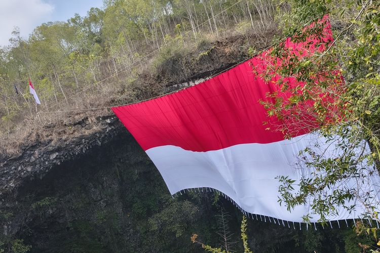 Bendera merah putih raksasa berkibar di mulut gua Luweng Ombo Dusun Petung, Desa Kalak, Kecamatan Donorojo, Kabupaten Pacitan, Jawa Timur, Senin (17/8/2026), dalam upacara peringatan HUT RI ke-81 yang disela kegiatan Gahvara Yava Expedition 2026.